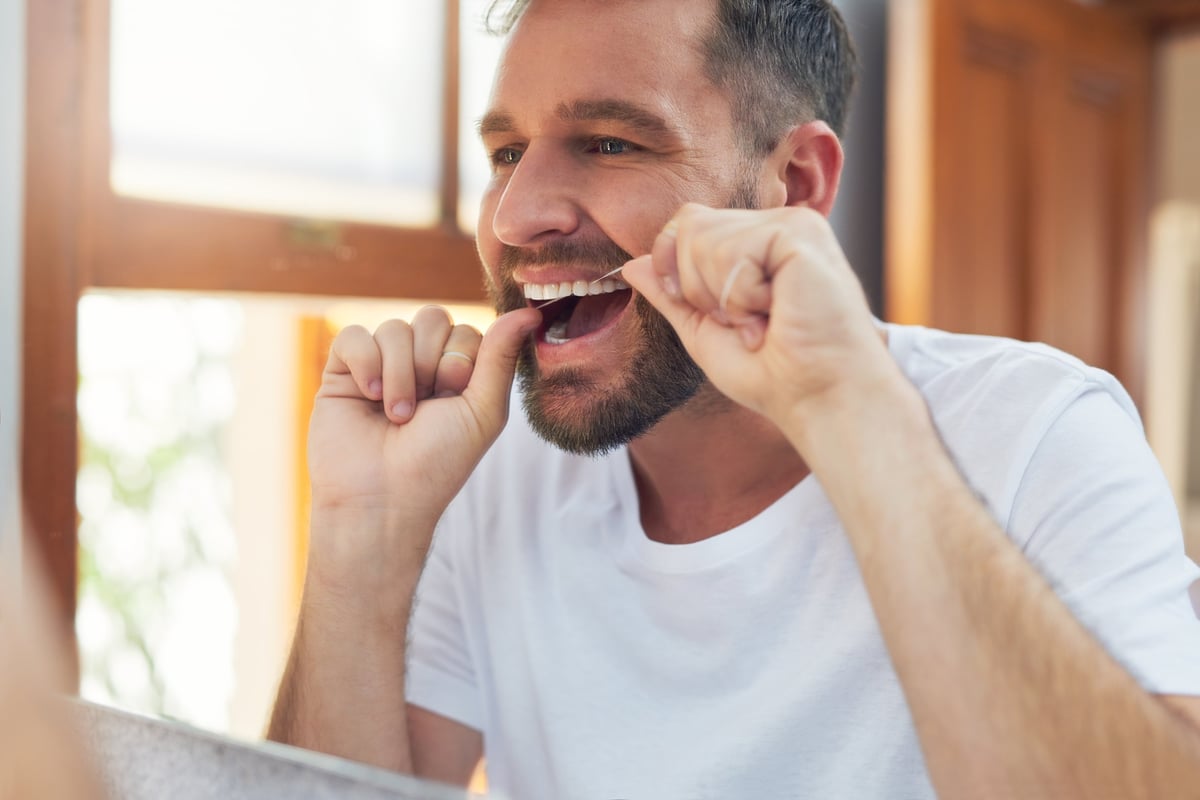 Shot of a handsome young man flossing his teeth in the bathroom