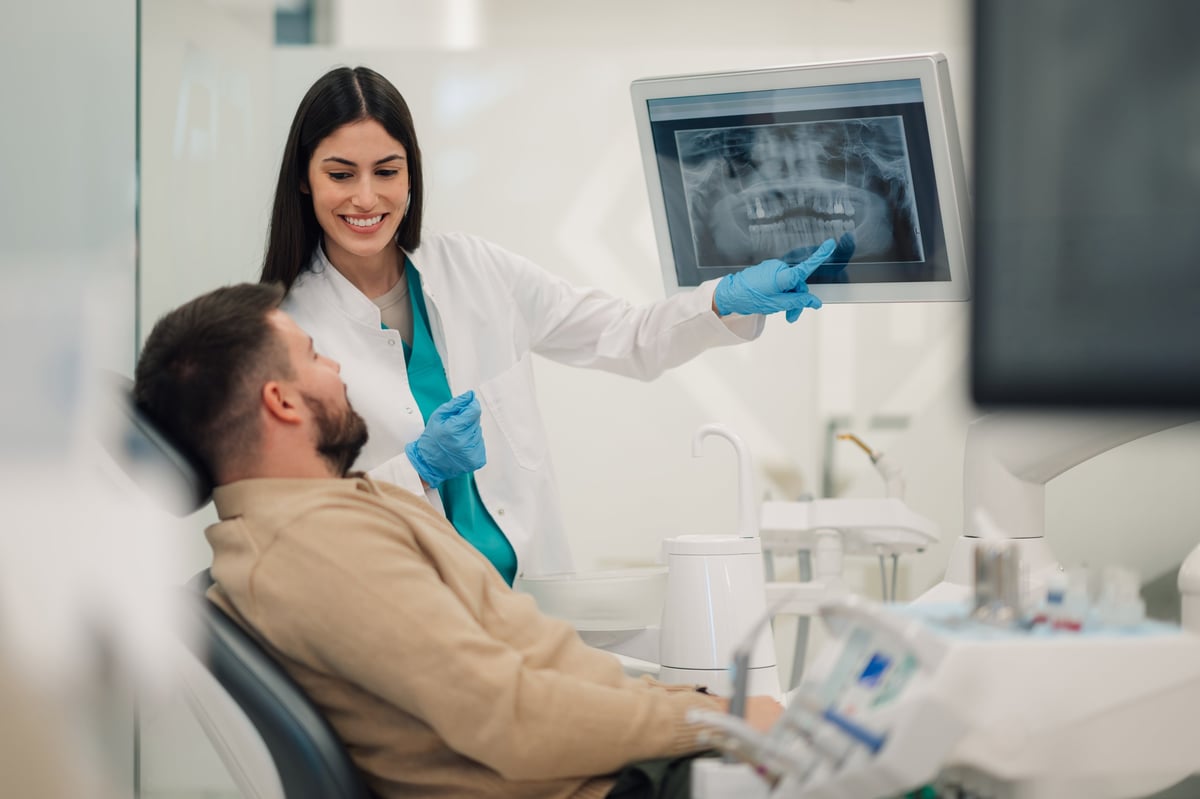 Female dentist showing a teeth x-ray to a male patient in a dental clinic