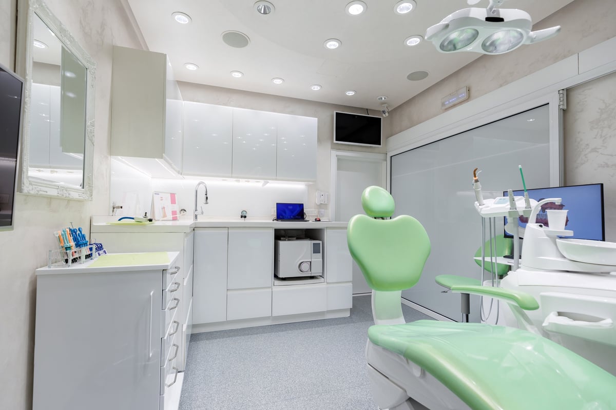 A sleek dental office featuring a green chair, bright lights, and modern amenities for patient care