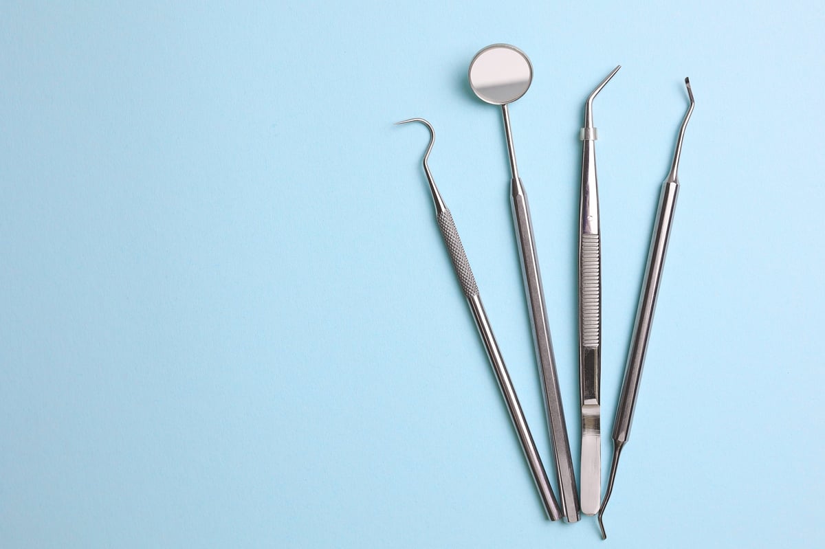 Dentist's tools and a dental model of teeth on a blue background close up
