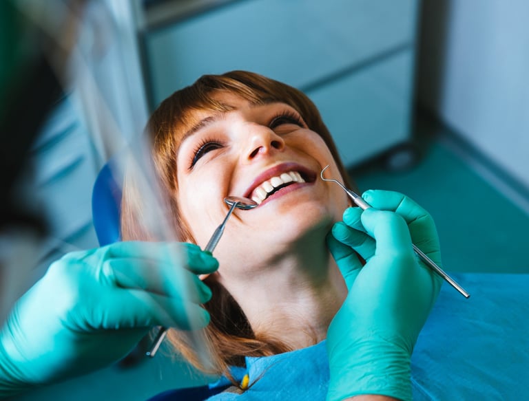 Smiling woman receiving dental examination from dentist wearing teal gloves and using dental tools