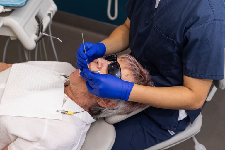 Dentist in blue gloves performing an oral examination on a patient in the dental chair.